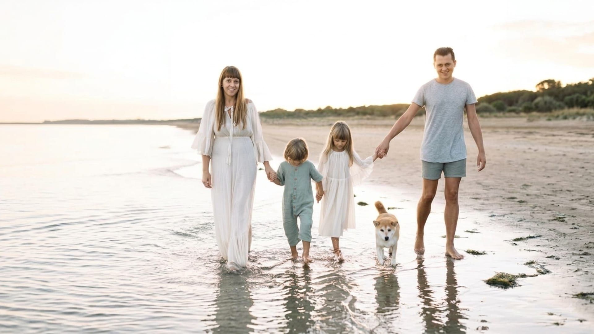 Una famiglia con bambini passeggia felice in spiaggia con il nostro Shiba Inu